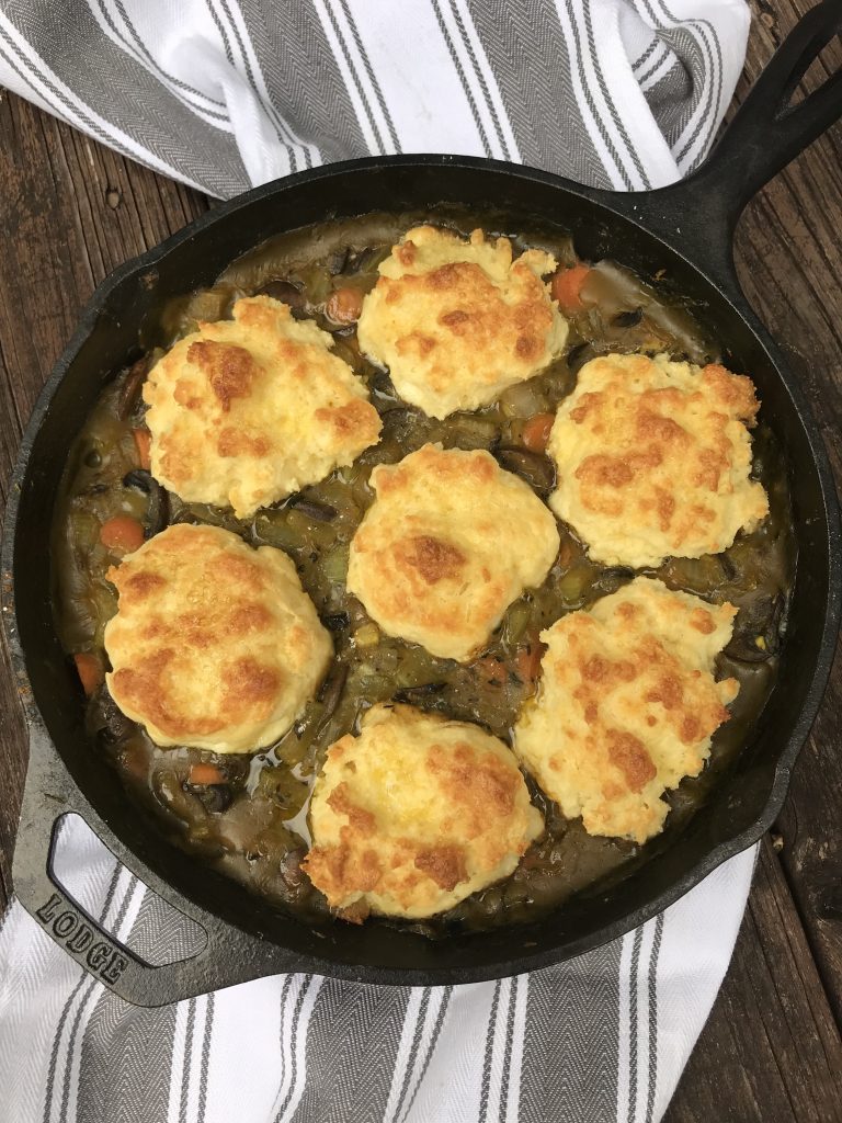 a skillet of vegetable pot pie with drop biscuits on top. 