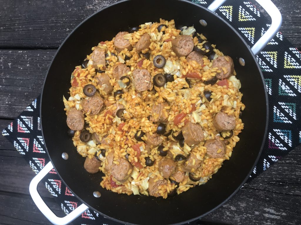 a pan of paella with artichoke, olives, and beyond sausage