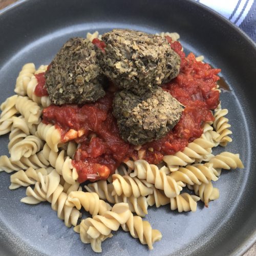 lentil meatballs on top of marinara sauce and rotini noodles