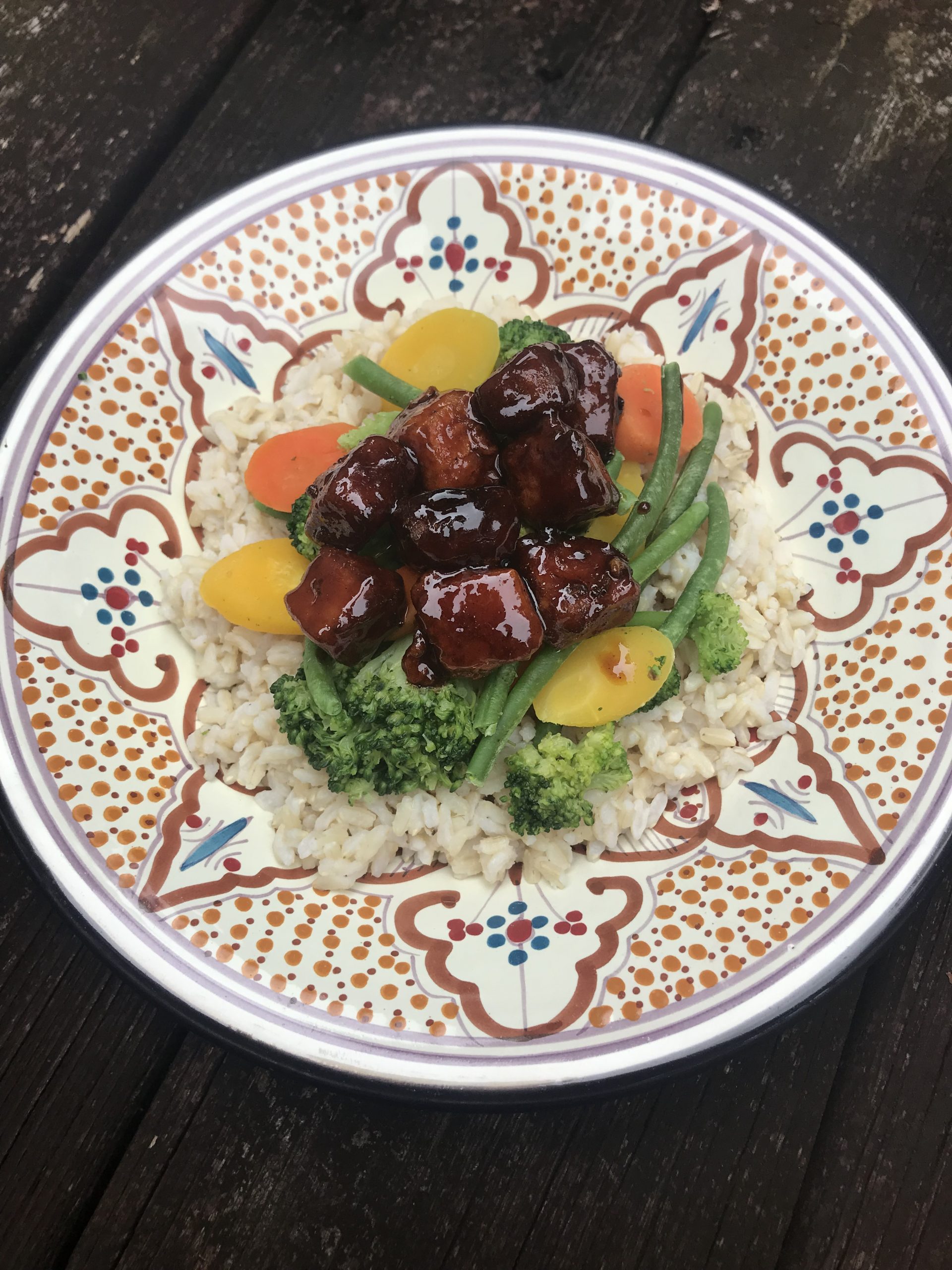 A bowl of brown rice, mixed vegetables, and topped with hoisin tofu