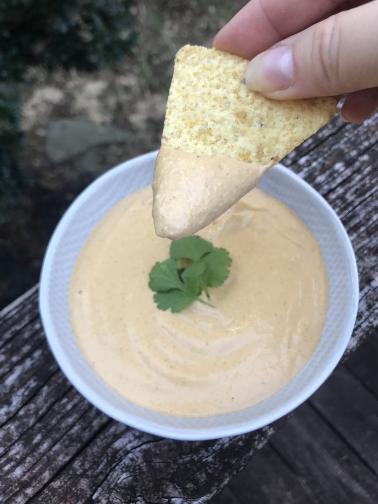 a bowl of cashew cream with a chip dipping in