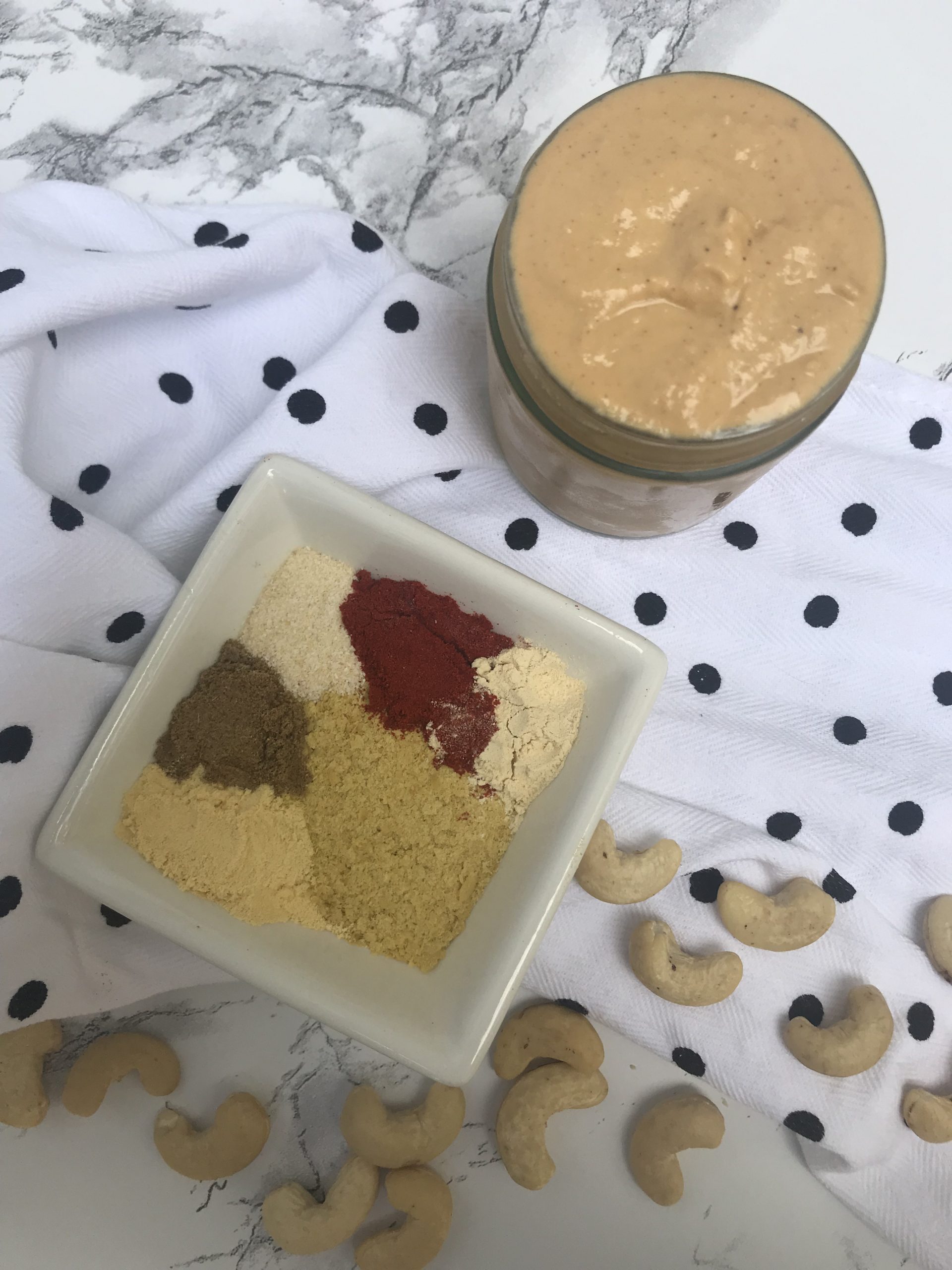 A jar of cashew cream and a bowl of the spices used