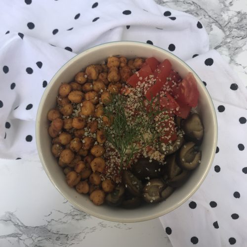 a bowl with chickpeas, tomatoes, black olives, and hemp hearts