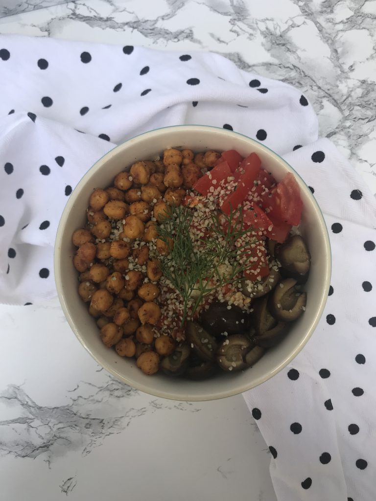 a bowl with chickpeas, tomatoes, black olives, and hemp hearts