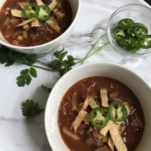 bowls of jackfruit tortilla soup topped with tortilla strips and jalapenos