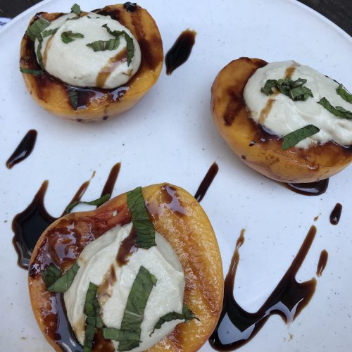 Grilled peaches and cream topped with balsamic glaze and strips of mint