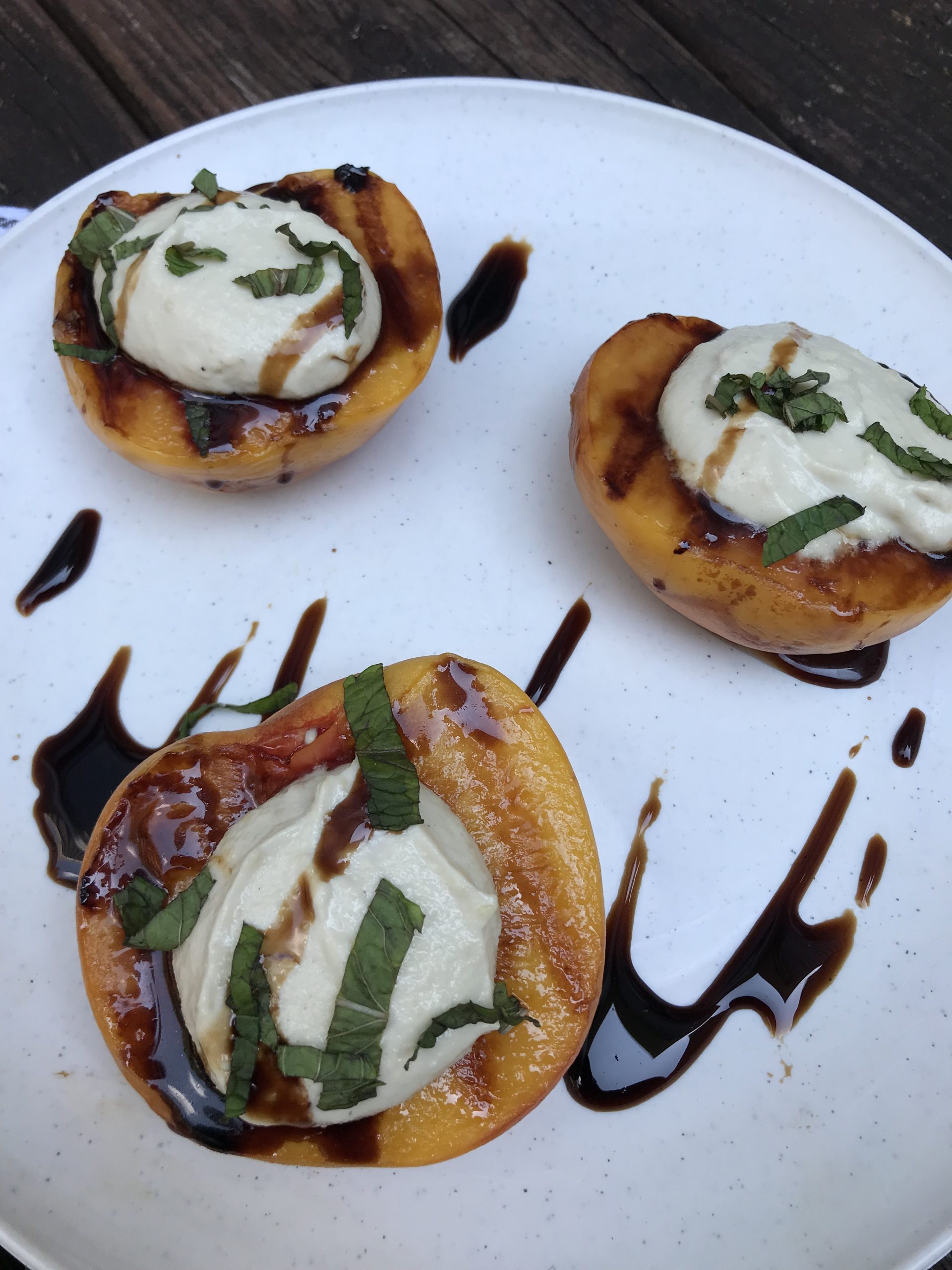 Grilled peaches and cream topped with balsamic glaze and strips of mint