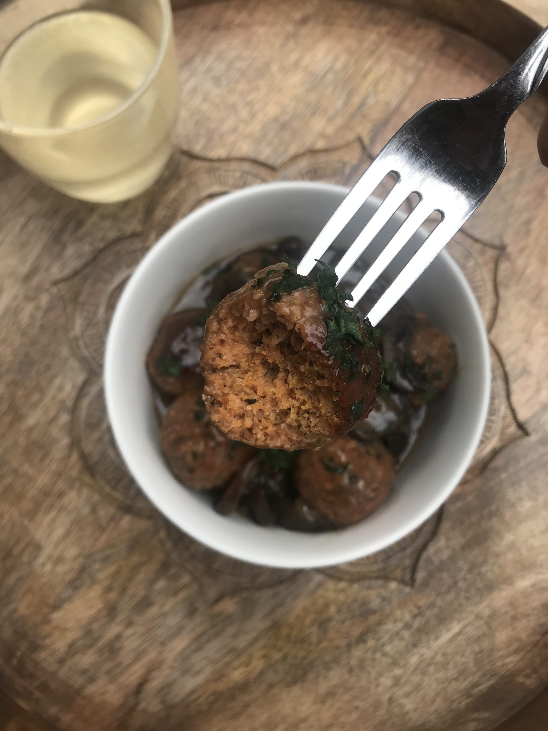 a bowl of meatballs marsala with one in the foreground with a bite taken out