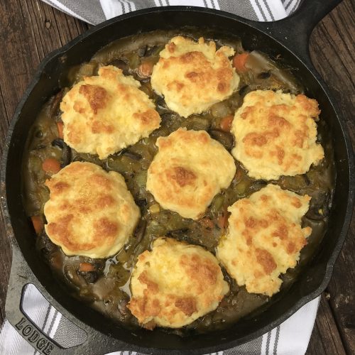 a skillet of vegetable pot pie with drop biscuits on top.