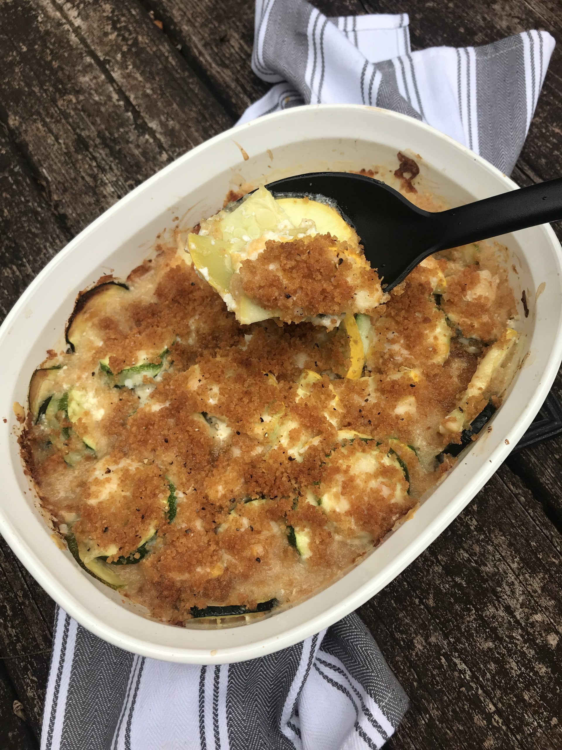 a dish of squash casserole with a spoon taking a scoop out