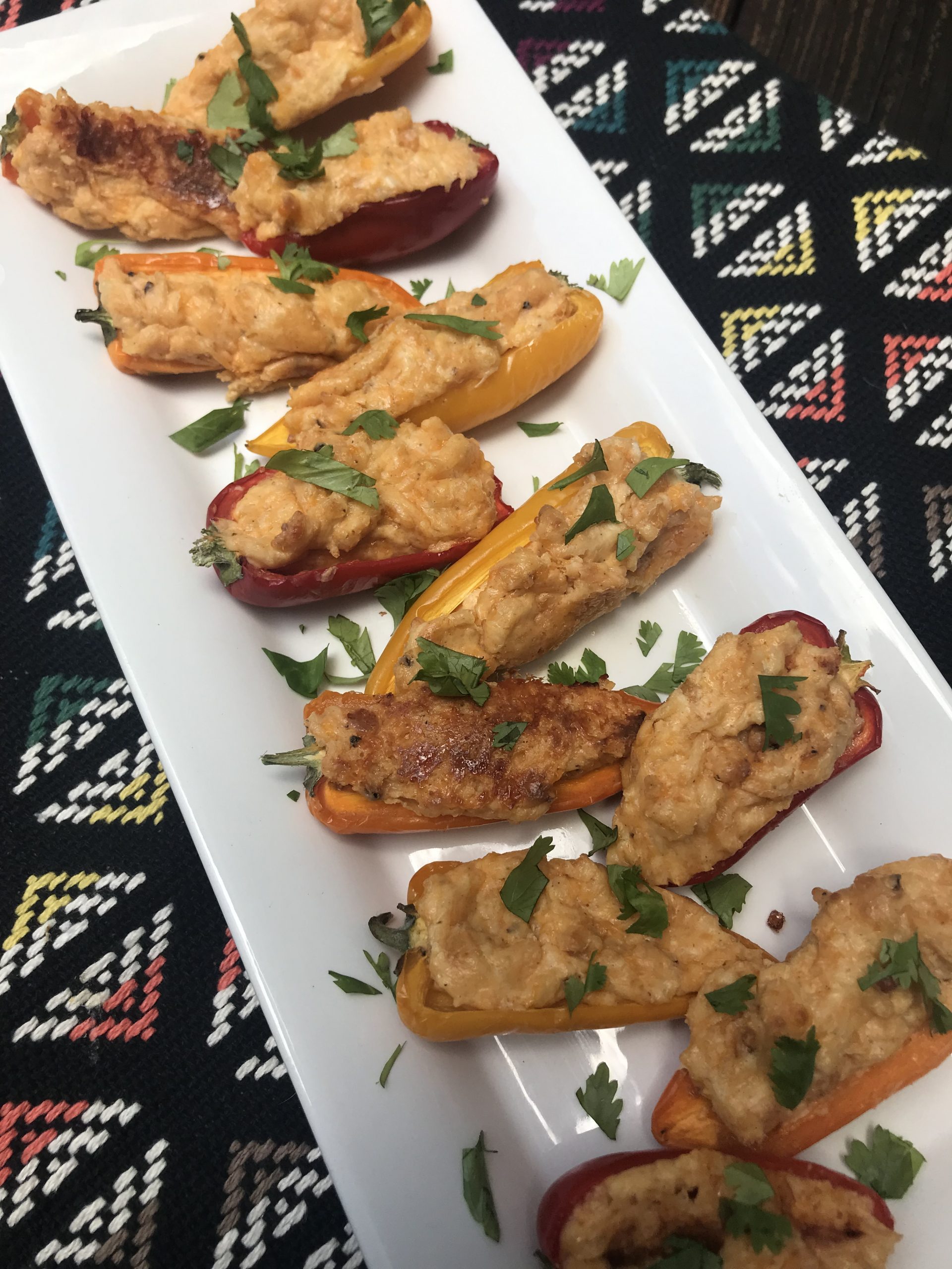 a plate of sweet pepper poppers stuffed with cream cheese and topped with cilantro