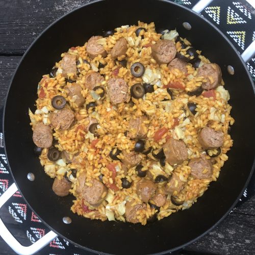 a pan of paella with artichoke, olives, and beyond sausage