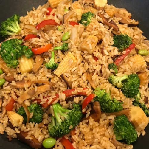 A wok of vegetable fried rice with broccoli, mushrooms, and baby corn