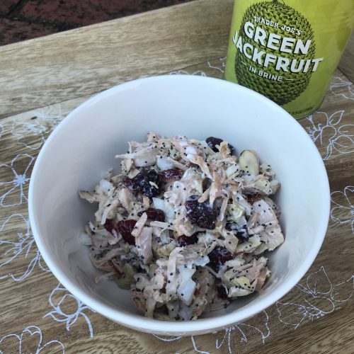 A bowl of cranberry almond jackfruit salad with a can of jackfruit in the background