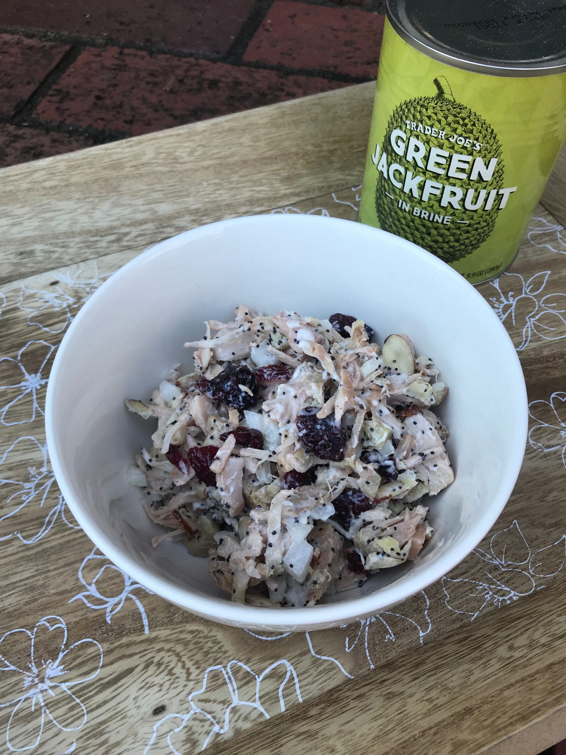 A bowl of cranberry almond jackfruit salad with a can of jackfruit in the background