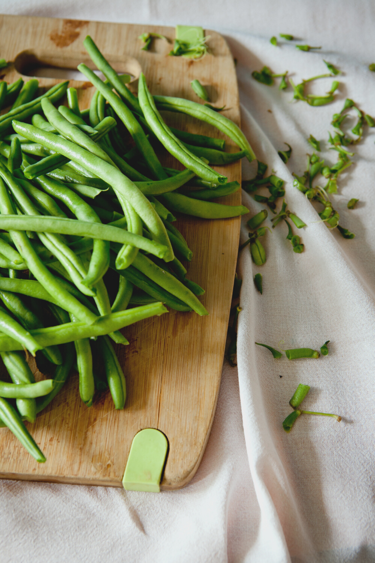 a cutting board with a stack of green beans