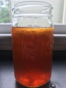 A jar of kombucha with a SCOBY on top
