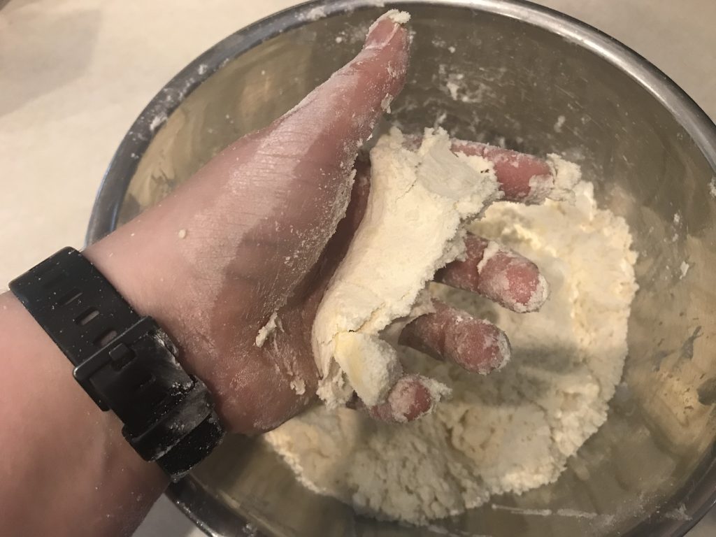 a bowl of dough with a hand squeezing the dough showing it holds its shape