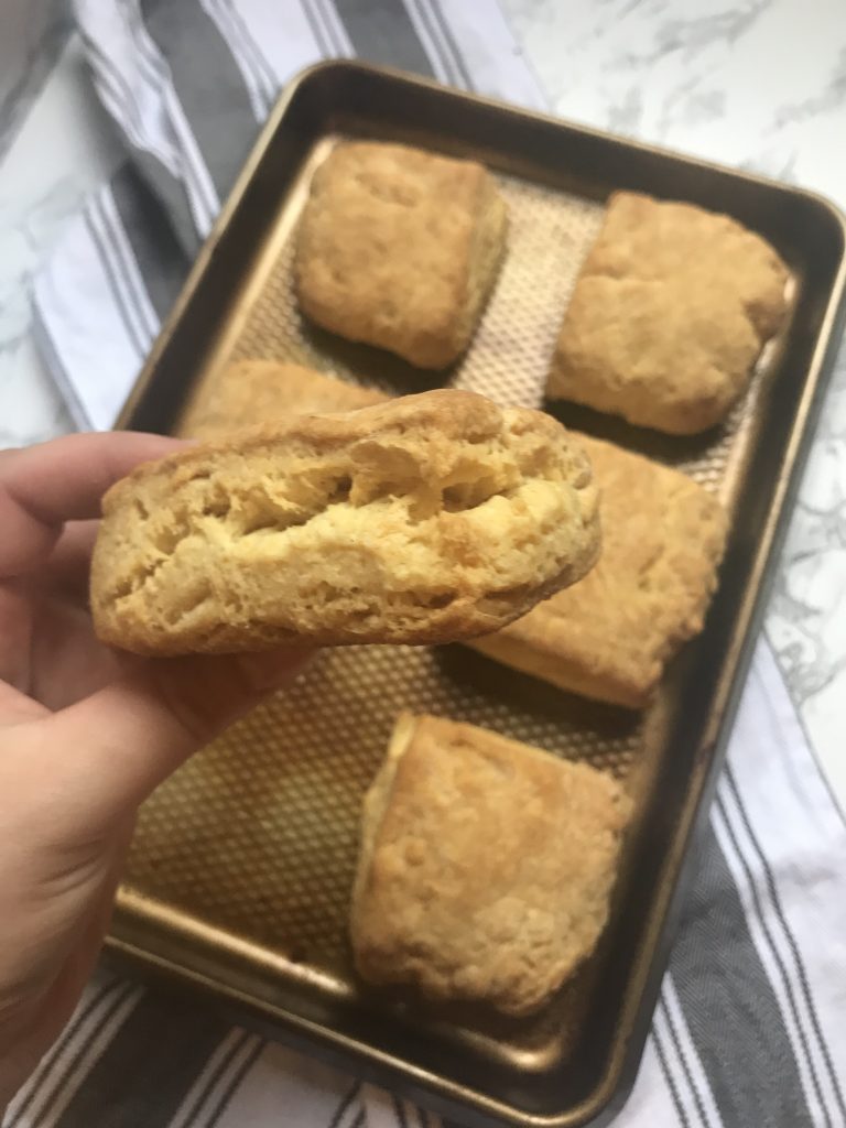 a tray of cooked biscuits with one held up in the foreground 