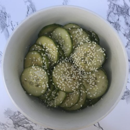 a bowl of cucumber salad topped with sesame seeds