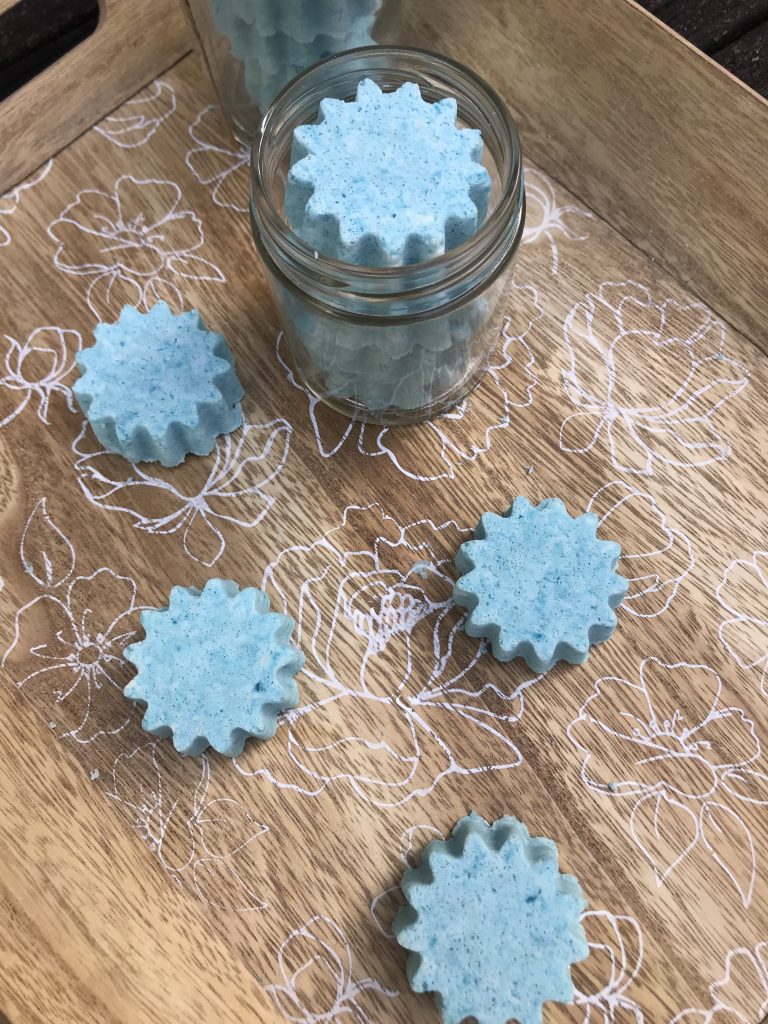 a jar of blue star bath bombs with more scattered around