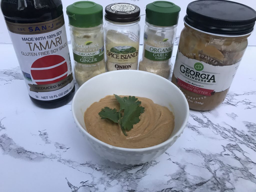 a bowl of the cashew sauce with the ingredients behind it 