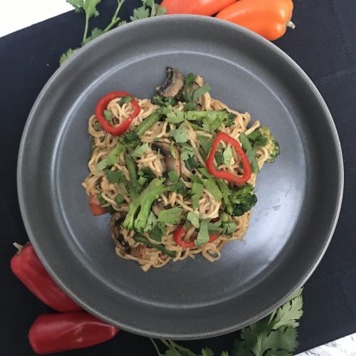 a plate with cashew noodles, veggies, and topped with cilantro