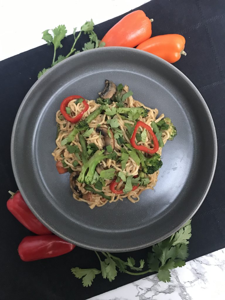 a plate with cashew noodles, veggies, and topped with cilantro