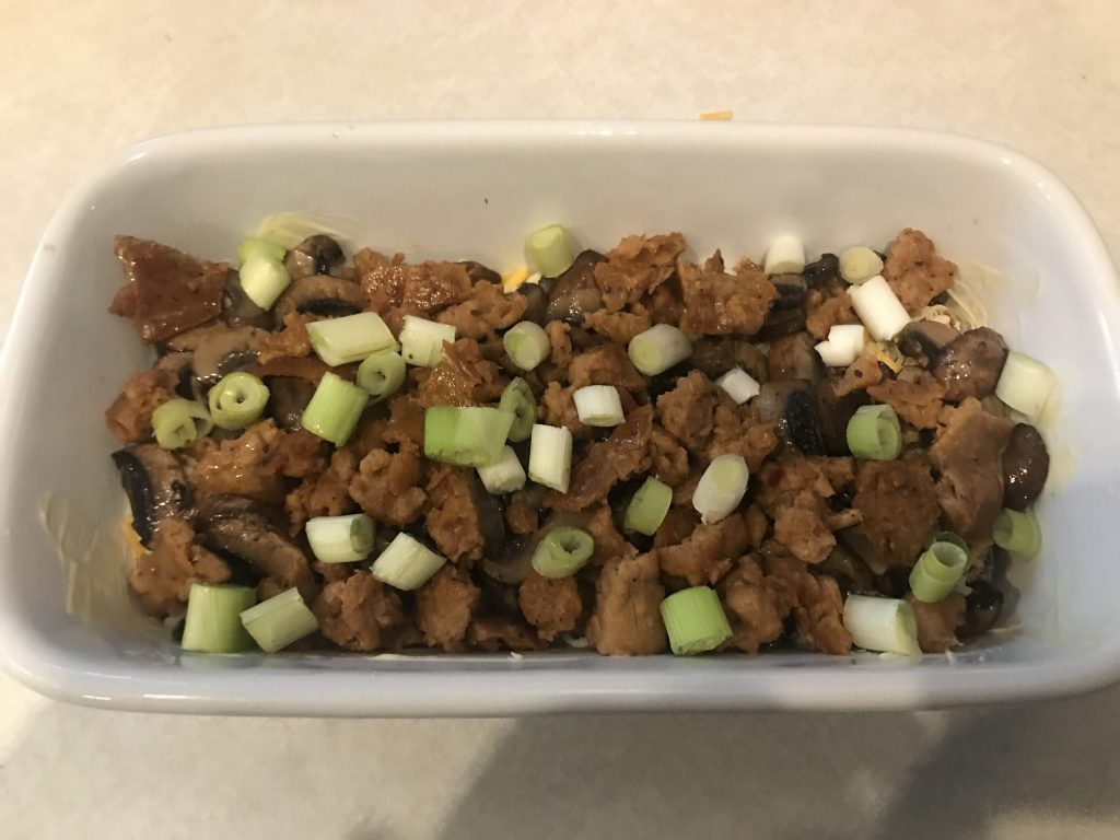 a loaf pan with beyond sausage and green onions layered in the dish