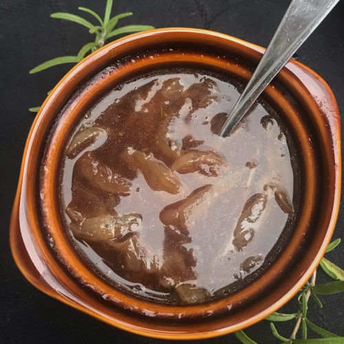 a bowl of French onion soup with a spoon in the crock