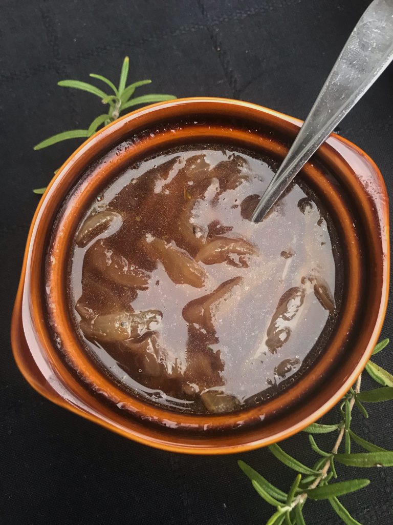 a bowl of French onion soup with a spoon in the crock