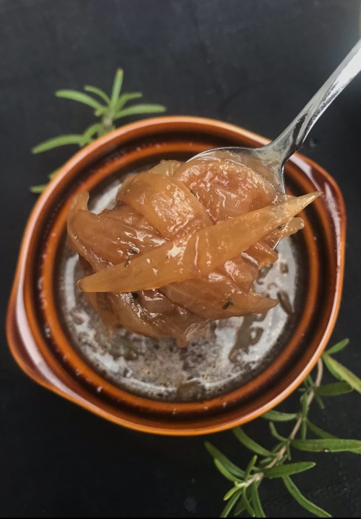 a bowl of French onion soup with a spoon scooping some onions out