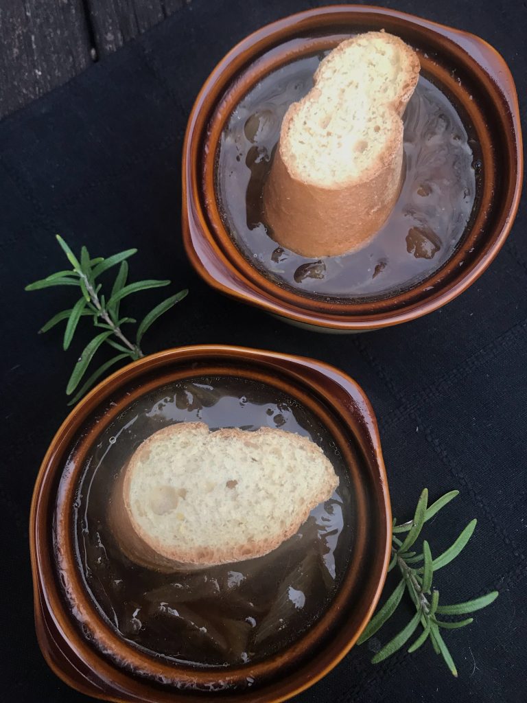 two crocks of plant-based French onion soup with slice of baguette on top