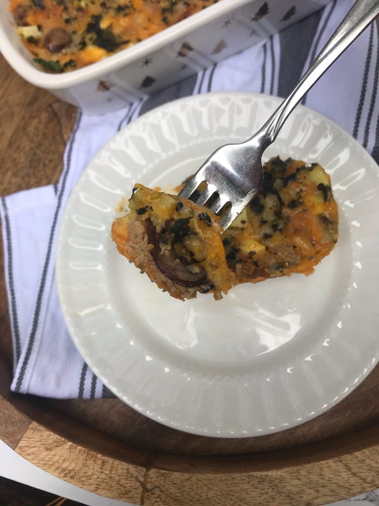 a slice of breakfast casserole with a fork holding up a bite toward the camera