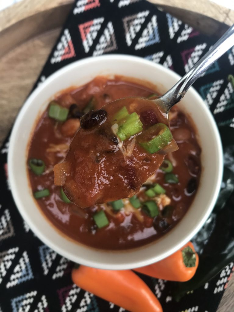 a bowl of chili with a spoon lifting a spoonful up