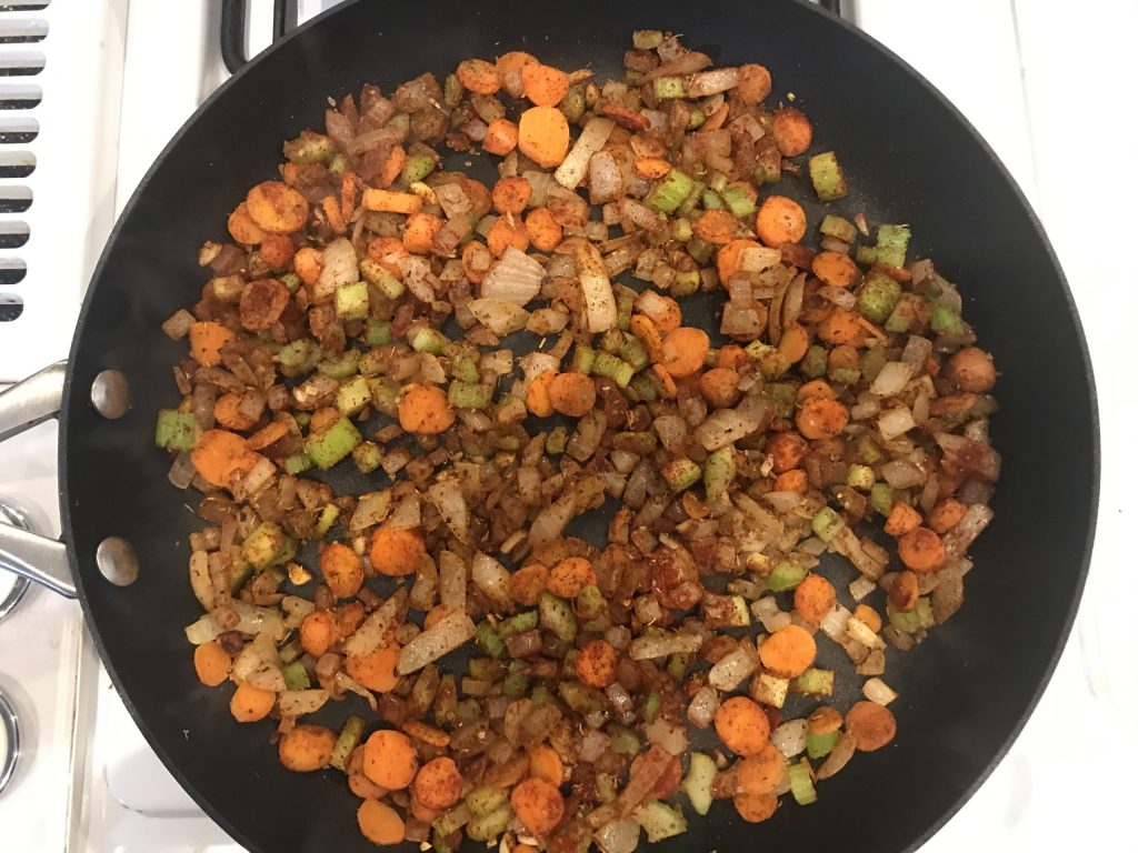 a pan with carrots, celery, onion, and spices