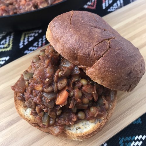 sloppy joe lentils on a bun with more lentils in the background