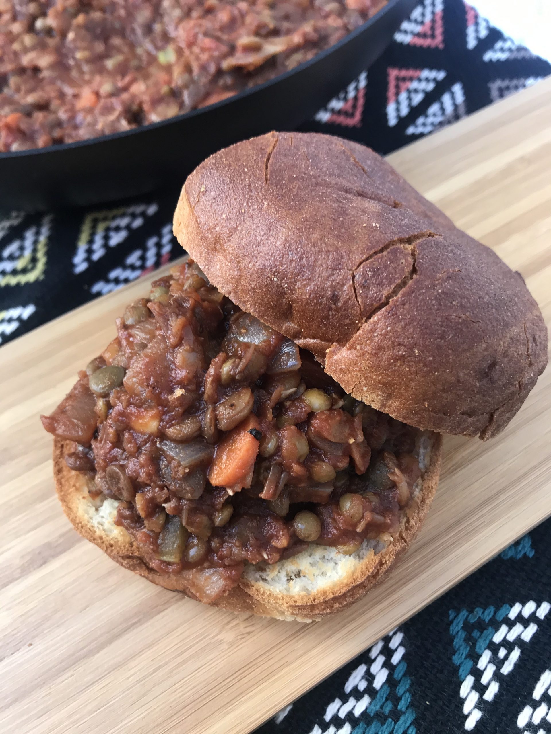 sloppy joe lentils on a bun with more lentils in the background