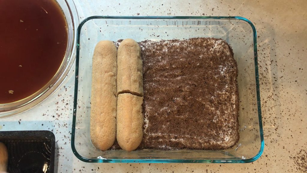 a couple lady fingers of the second layer placed on top of the grated chocolate