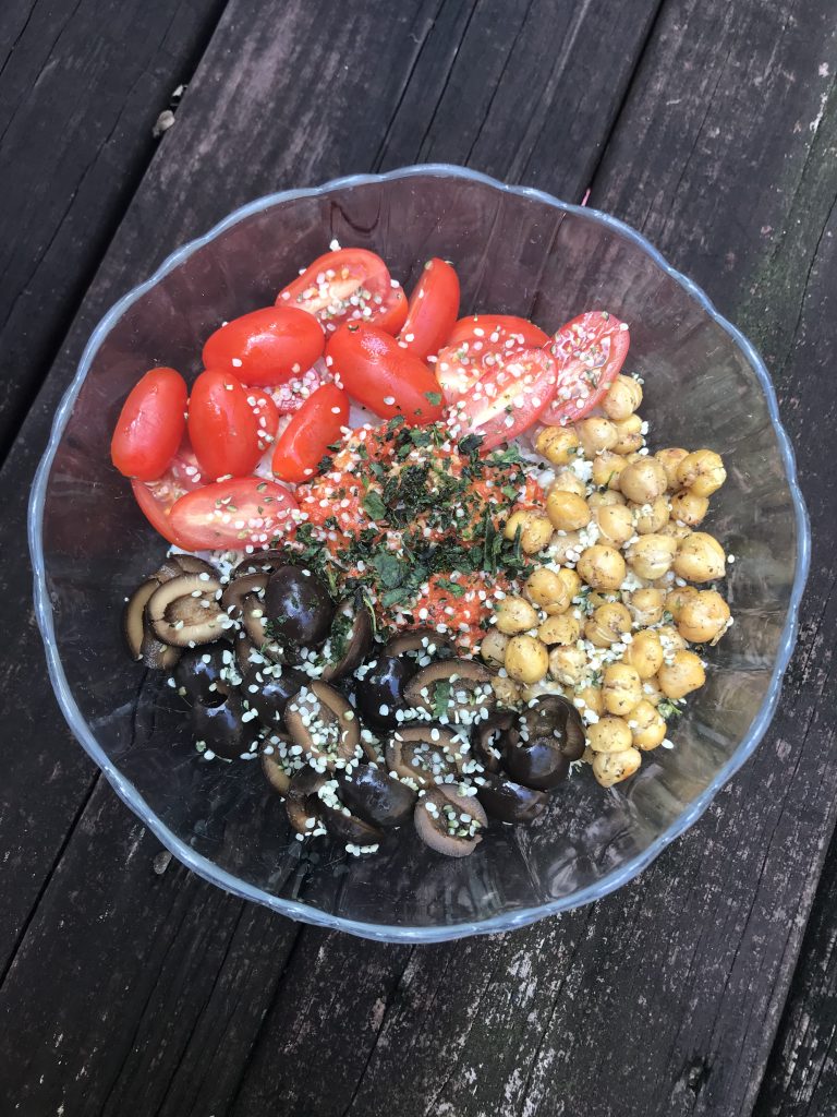 a rice bowl with tomatoes, olives, chickpeas, and hemp hearts