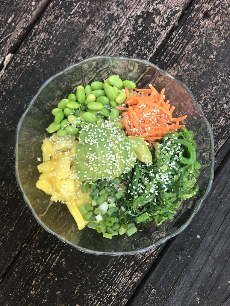 rice bowl with edamame, pineapple, seaweed salad, carrot, avocado, and sesame seeds